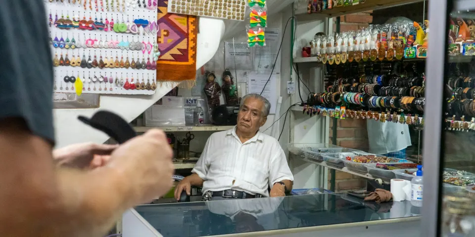 Dueño de una tienda de artesanías atendiendo a un cliente detrás del mostrador