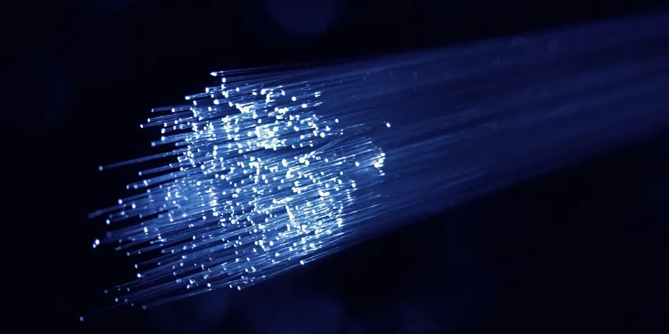 Hilos de fibra óptica iluminados en azul sobre un fondo oscuro