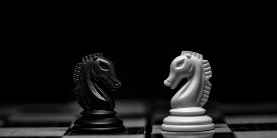 Dos caballos de ajedrez enfrentados sobre un tablero