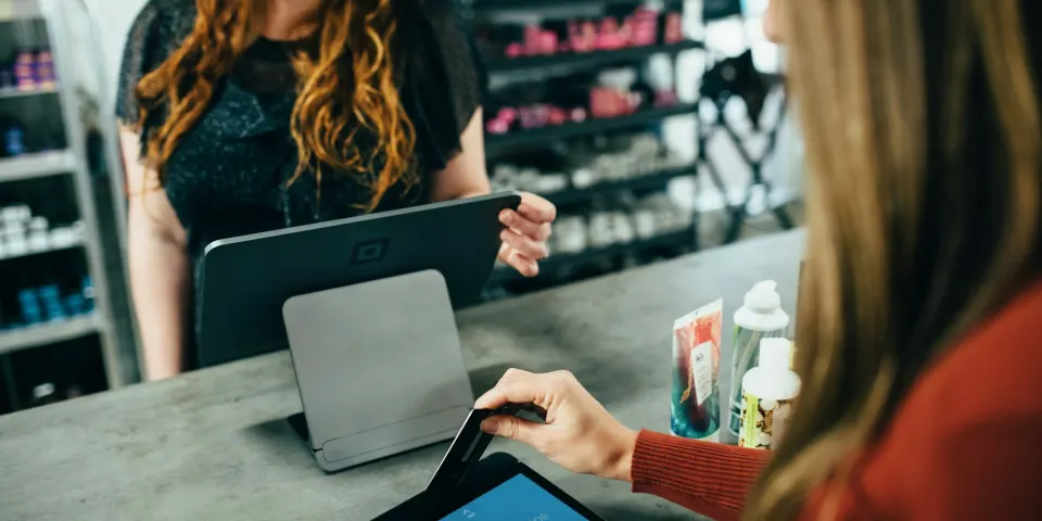 Dueña de un negocio usando una tableta para registrar una venta en el mostrador