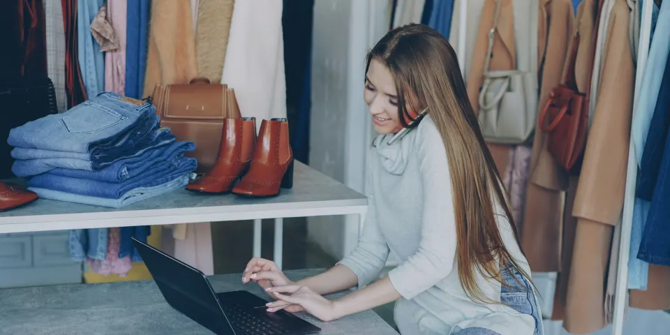 Emprendedora trabajando en su computador portátil dentro de su tienda de ropa