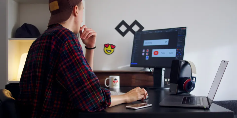 Diseñador trabajando en su computador en un escritorio con pantallas