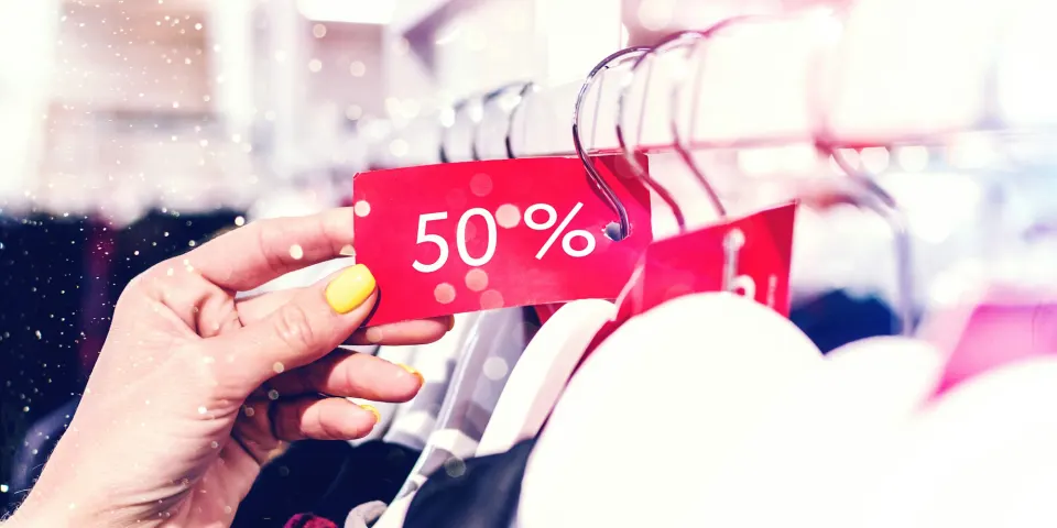 Mano sosteniendo una etiqueta de descuento del 50 % en una tienda de ropa