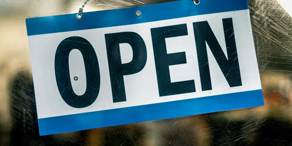 Letrero azul y blanco con la palabra Open colgado en la puerta de un negocio