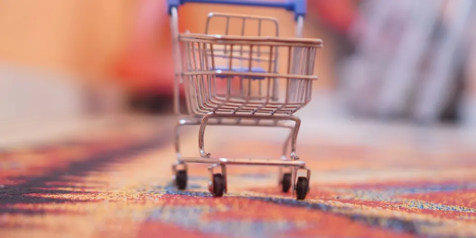 Pequeño carrito de compras sobre una superficie de colores