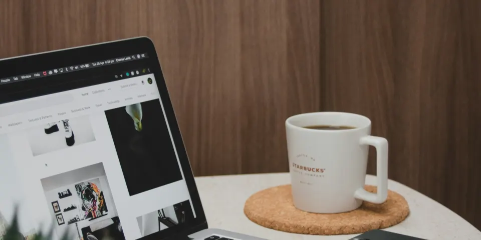Computador portátil abierto con un sitio personal junto a una taza de café