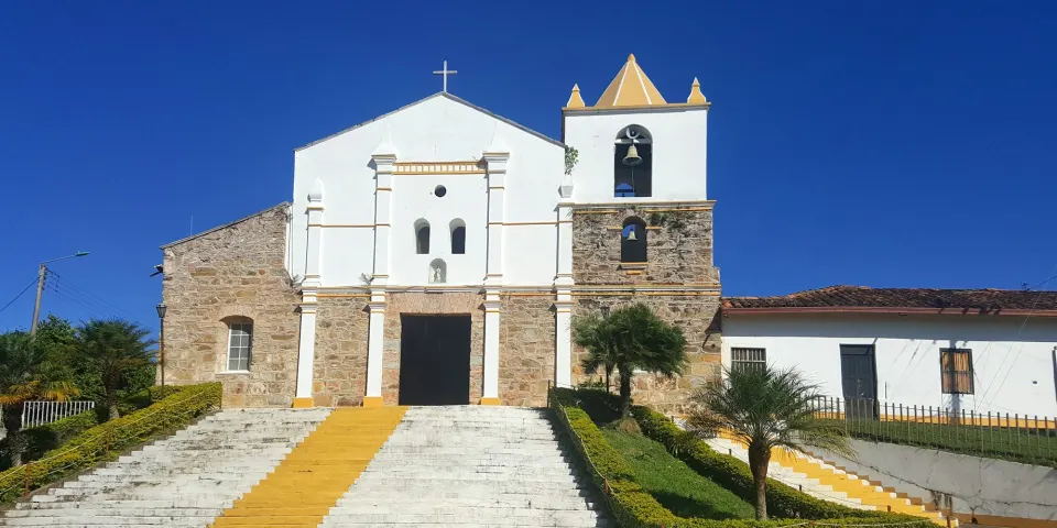 Iglesia blanca con campanario y escalinata en la plaza de un pueblo colombiano