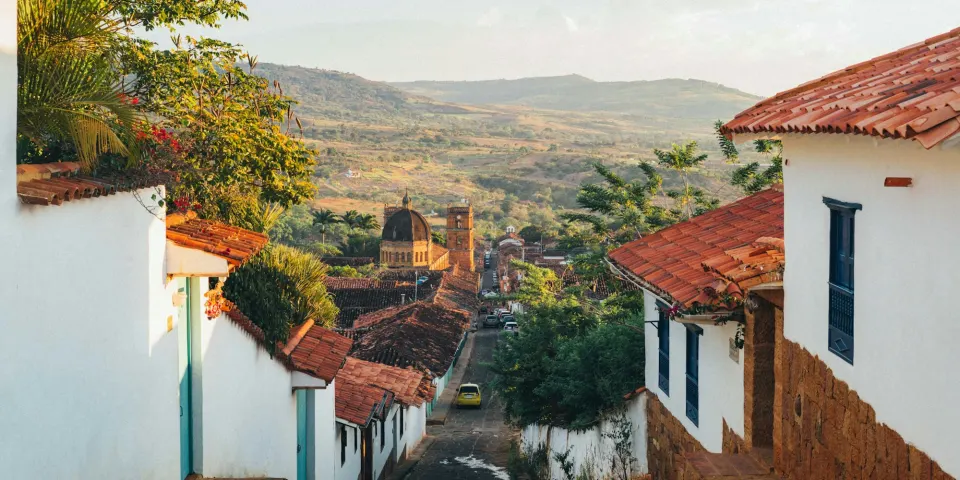 Calle empinada de un pueblo colonial con casas blancas y tejados rojos