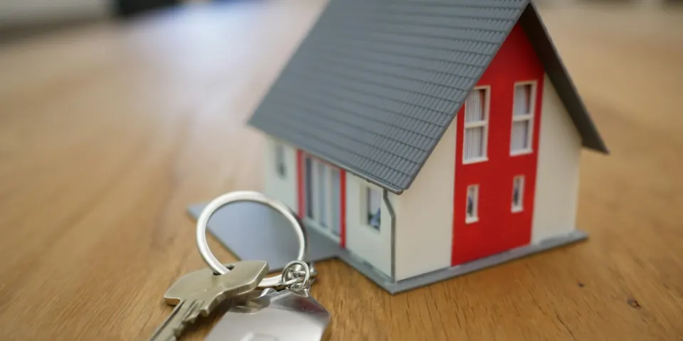 Maqueta de una casa con un llavero sobre una mesa de madera