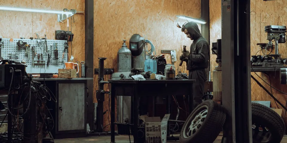 Mecánico trabajando dentro de un taller con herramientas y llantas