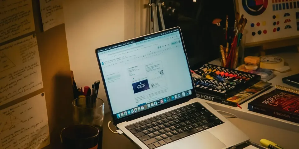 Escritorio creativo con un computador portátil, lámpara y materiales de trabajo