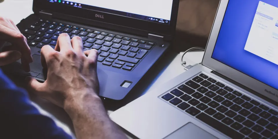 Dos computadores portátiles abiertos lado a lado sobre una mesa de trabajo