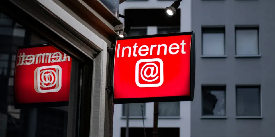 Letrero luminoso rojo con la palabra Internet y el símbolo arroba en una fachada
