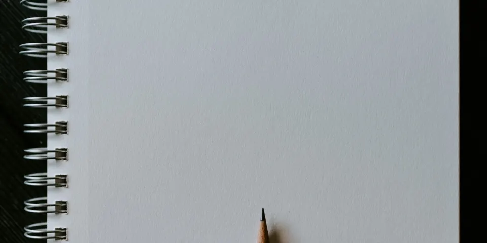 Cuaderno en blanco con un lápiz sobre una mesa gris