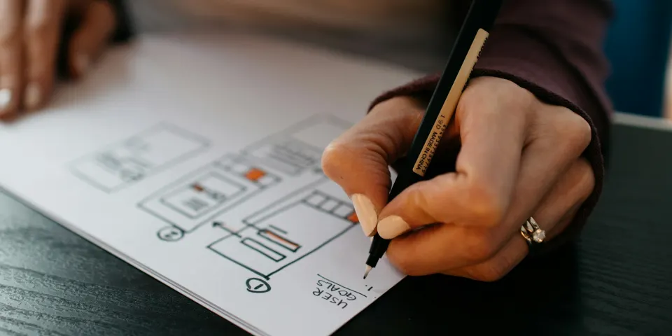 Manos dibujando bocetos de páginas web en papel con un bolígrafo